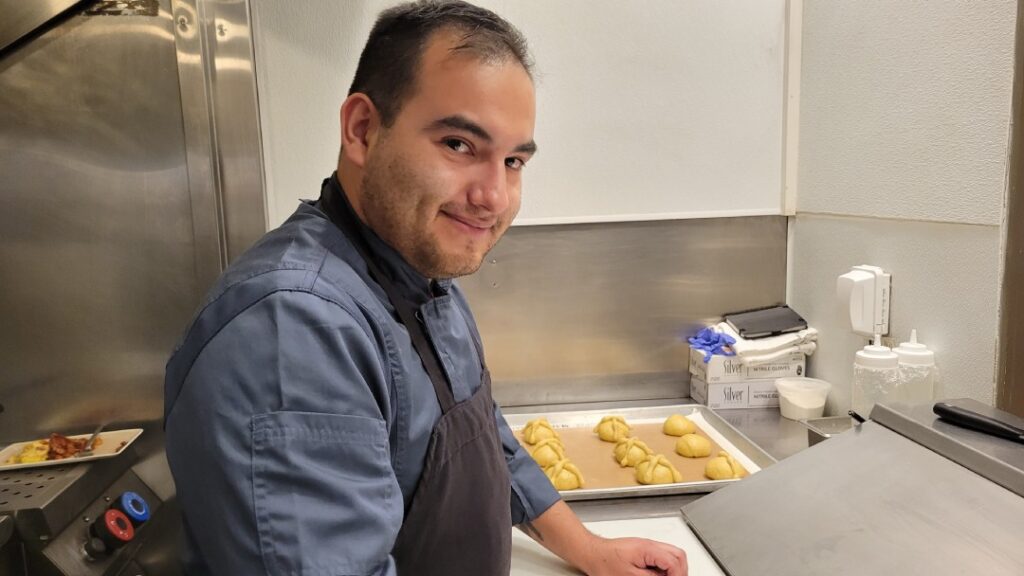 chef de uniforme gris con negro elaborando pan de muerto