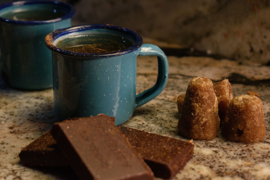 taza de peltre con chocolate caliente y piloncillo de decoracion